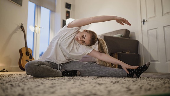 Eine Frau macht Yoga auf einem Teppich