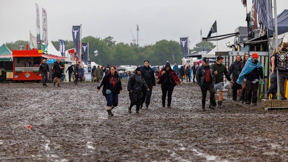 Festivalbesucher laufen über schlammiges Gelände.