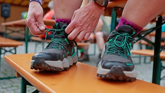 Wanderschuhe werden auf einer Bank auf dem Marktplatz in Wernigerode geschnürt. 