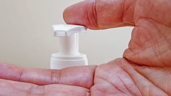 Nahaufnahme einer Hand die einen Druckspender bedient