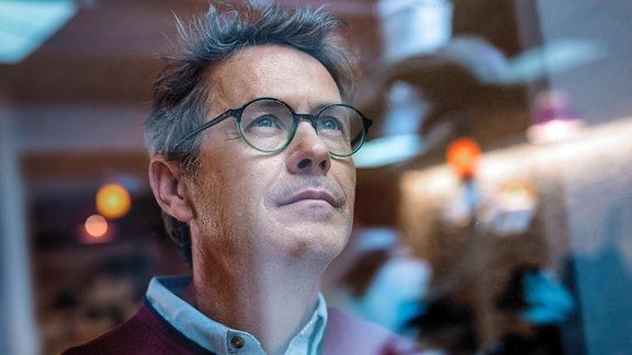 Geschäftsmann mit Brille, gesehen durch Glas im Büro