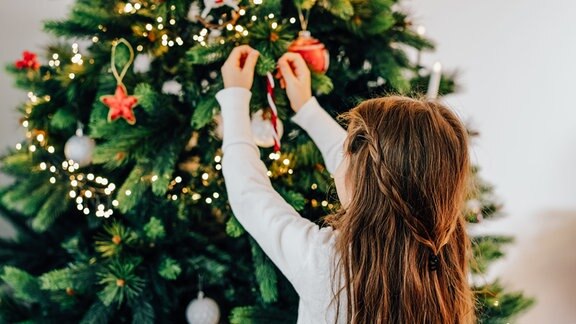 Kind schmückt den Weihnachtsbaum
