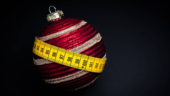 Maßband umschließt Weihnachtsbaumkugel