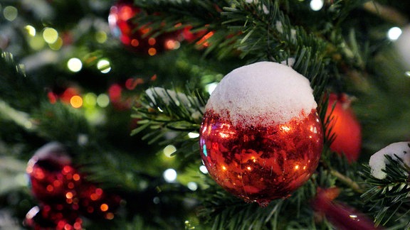 Schnee auf weihnachtlich geschmücktem Tannenbaum