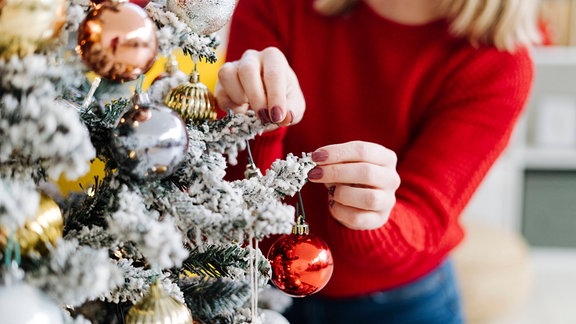 Eine Frau schmückt einen Weihnachtsbaum