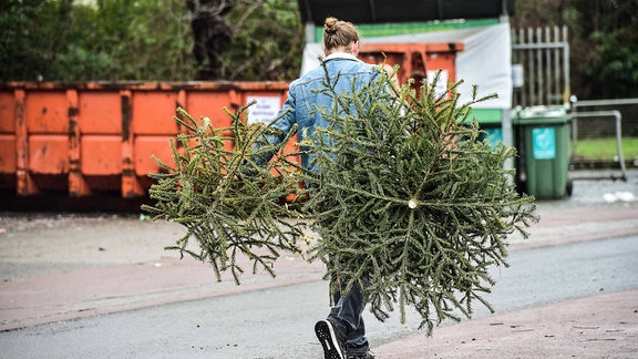 Ein Mann entsorgt einen Weihnachtsbaum