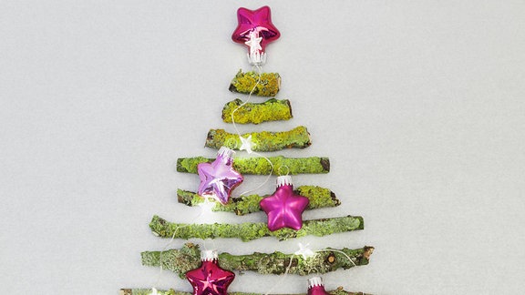 Weihnachtsbaum aus moosbewachsenen Zweigen und Weihnachtsschmuck.