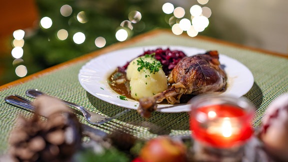 Eine Portion Gänsekeule mit Rotkraut und Klößen steht auf einem Tisch im Restaurant