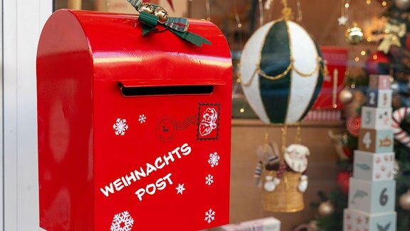 Weihnachtspost, steht auf einem Briefkasten an einem Ladengeschäft mit weihnachtlicher Dekoration