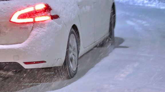 Ein Rücklicht eines weißen PKW im Winterwetter