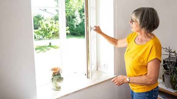 Eine Seniorin lüftet die Wohnung (gestellte Szene). 
