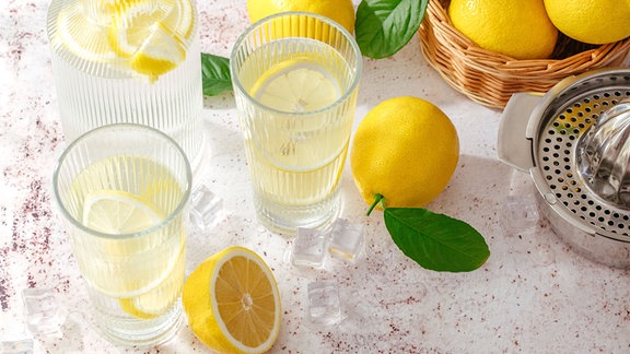 Zitronen in Wassergläsern und als Frucht daneben auf einem dekorierten Tisch