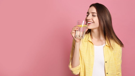 Eine Frau trinkt aus einem Glas Zitronenwasser