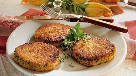 Französische Zucchinipuffer auf einem Teller mit Wein und Baguette