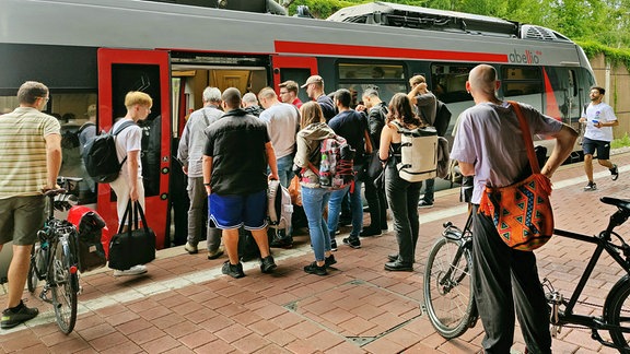 Viele Menschen drängen in einen Nahverkehrszug auf einem Bahnhof.
