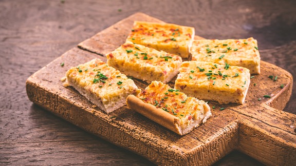 Zwiebelkuchenstücke auf einem Holzbrett